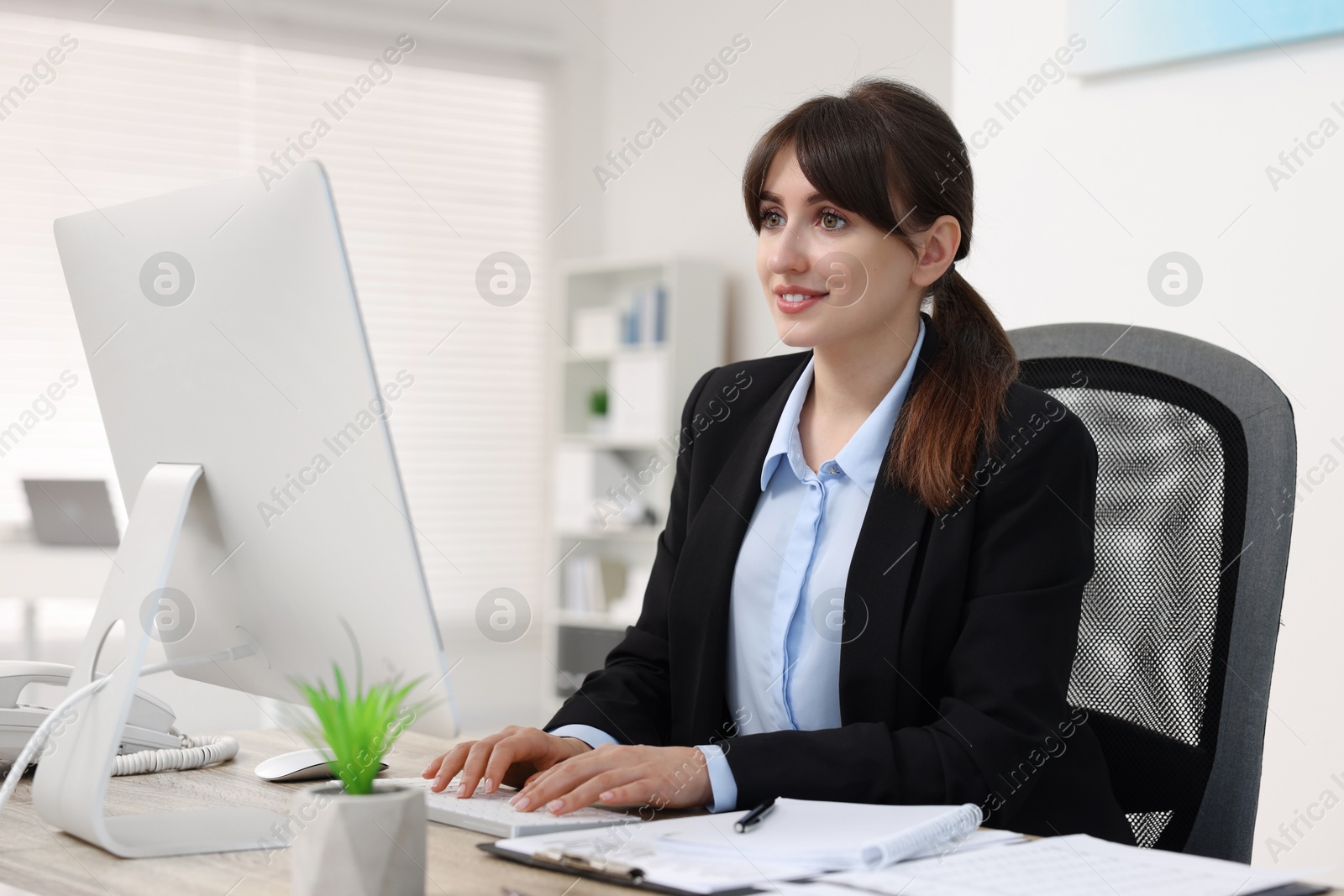 Photo of Smiling secretary working at table in office