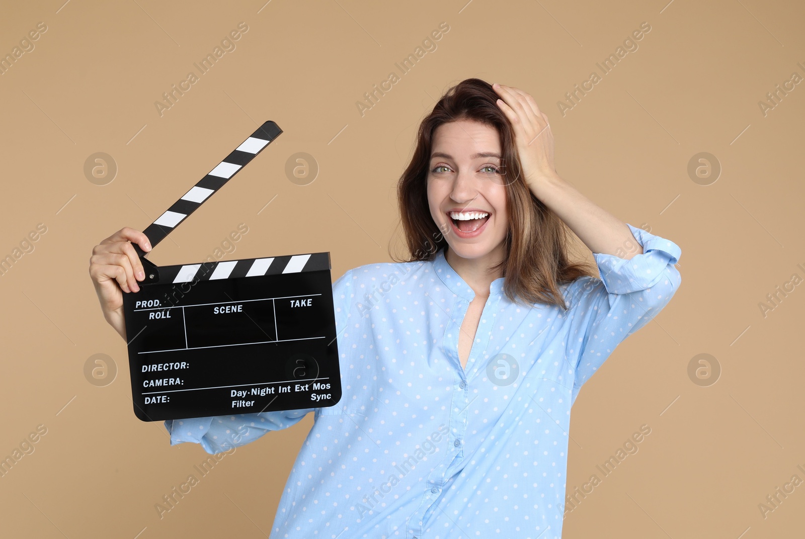 Photo of Making movie. Happy woman with clapperboard on beige background