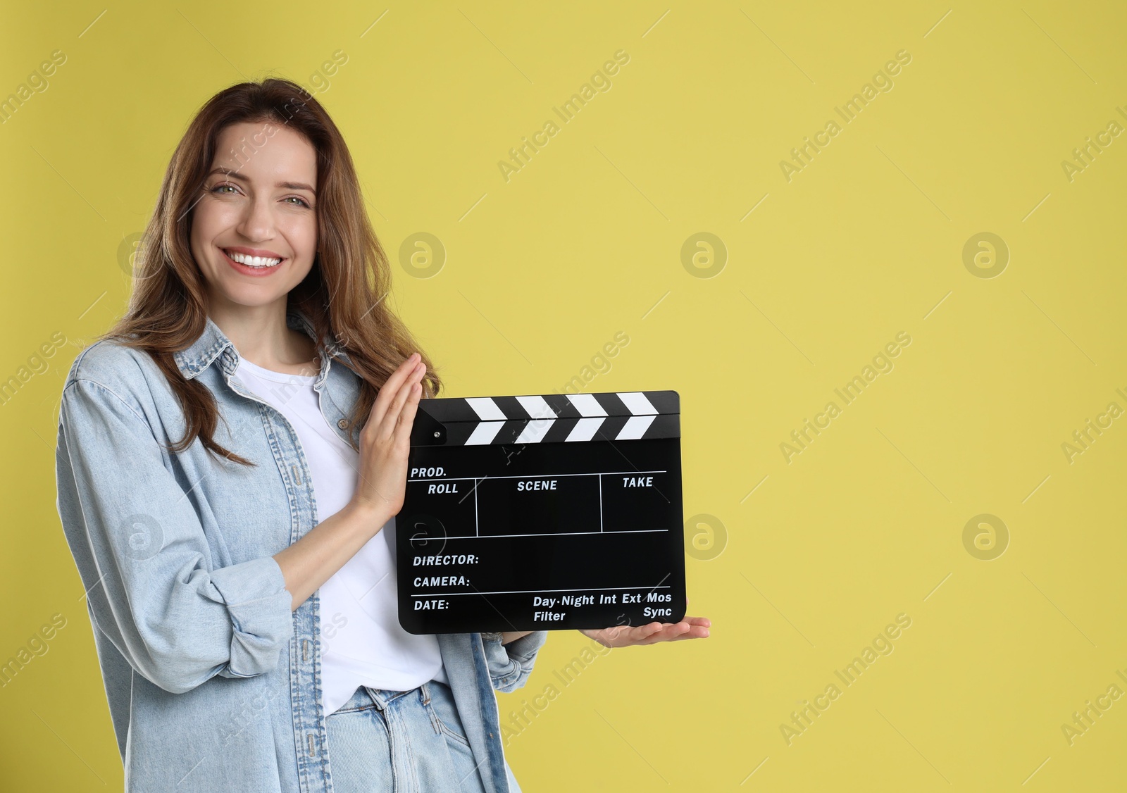 Photo of Making movie. Smiling woman with clapperboard on yellow background. Space for text