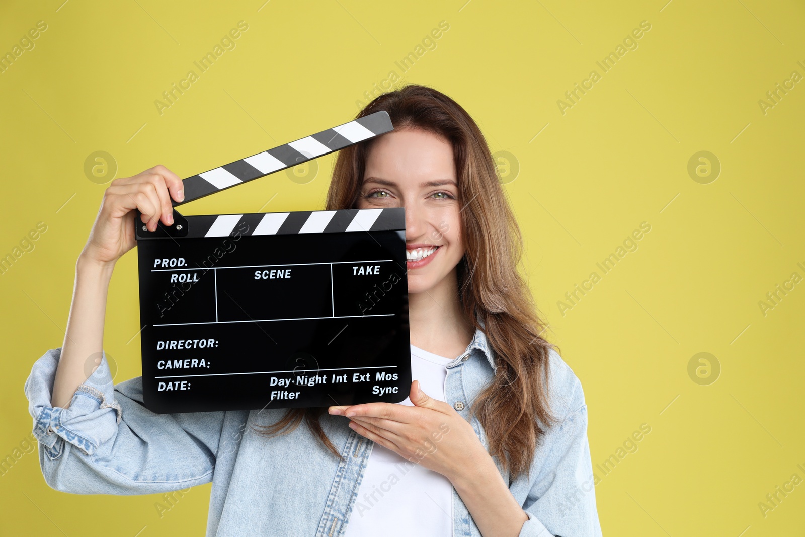 Photo of Making movie. Smiling woman with clapperboard on yellow background