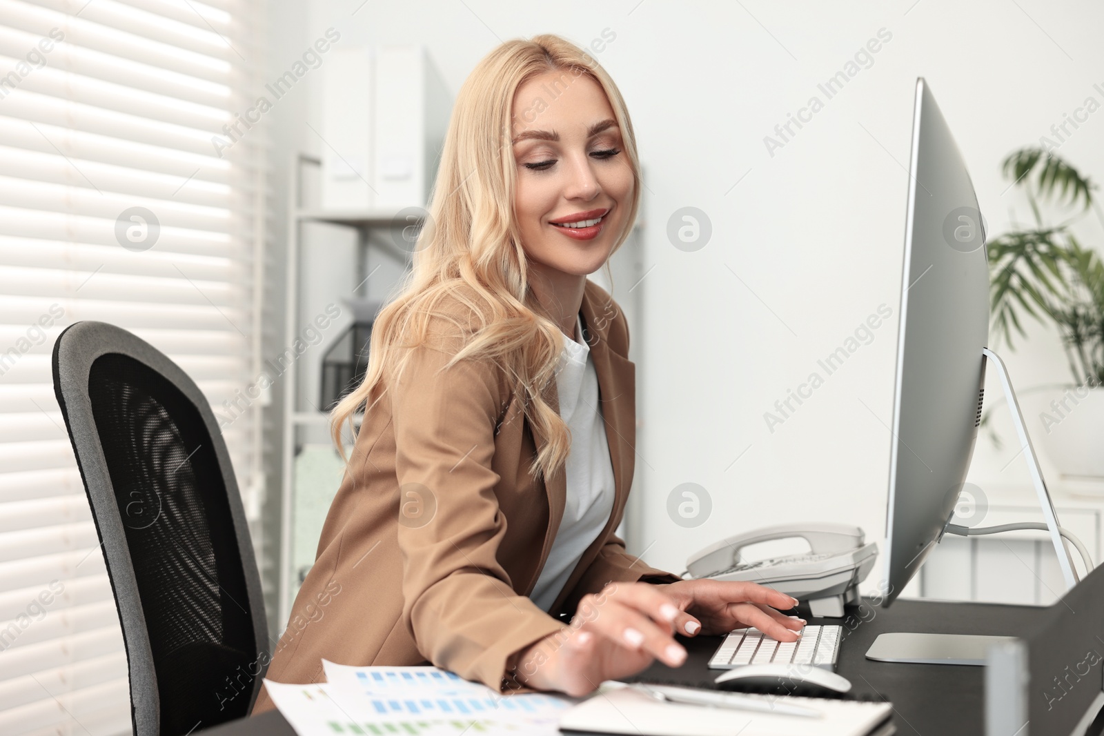 Photo of Happy secretary working at table in office