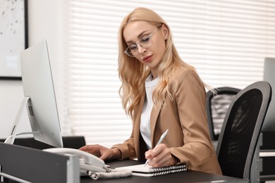 Secretary taking notes at table in office