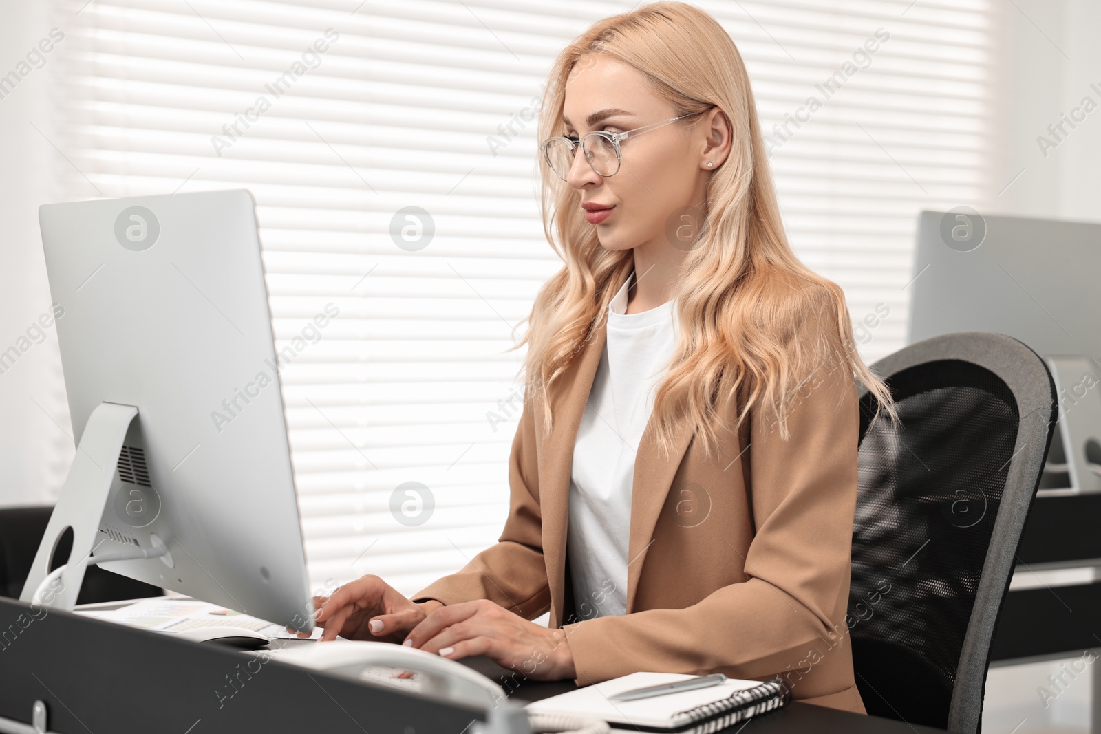 Photo of Secretary working on computer at table in office