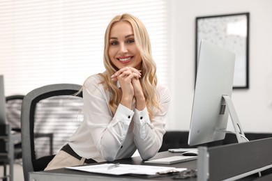 Portrait of happy secretary at table in office