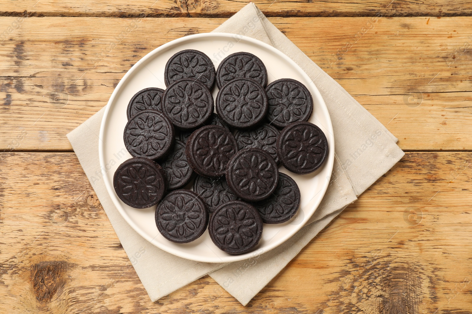 Photo of Plate with tasty sandwich cookies on wooden table, top view