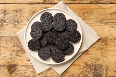 Plate with tasty sandwich cookies on wooden table, top view