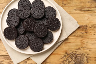 Photo of Plate with tasty sandwich cookies on wooden table, top view. Space for text