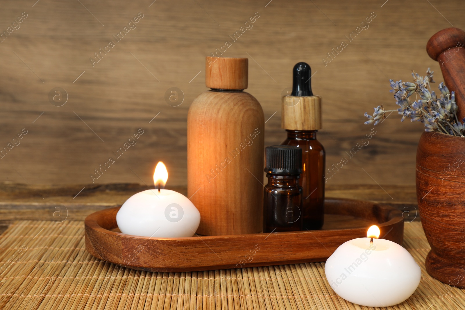 Photo of Different aromatherapy products, burning candles and mortar on table