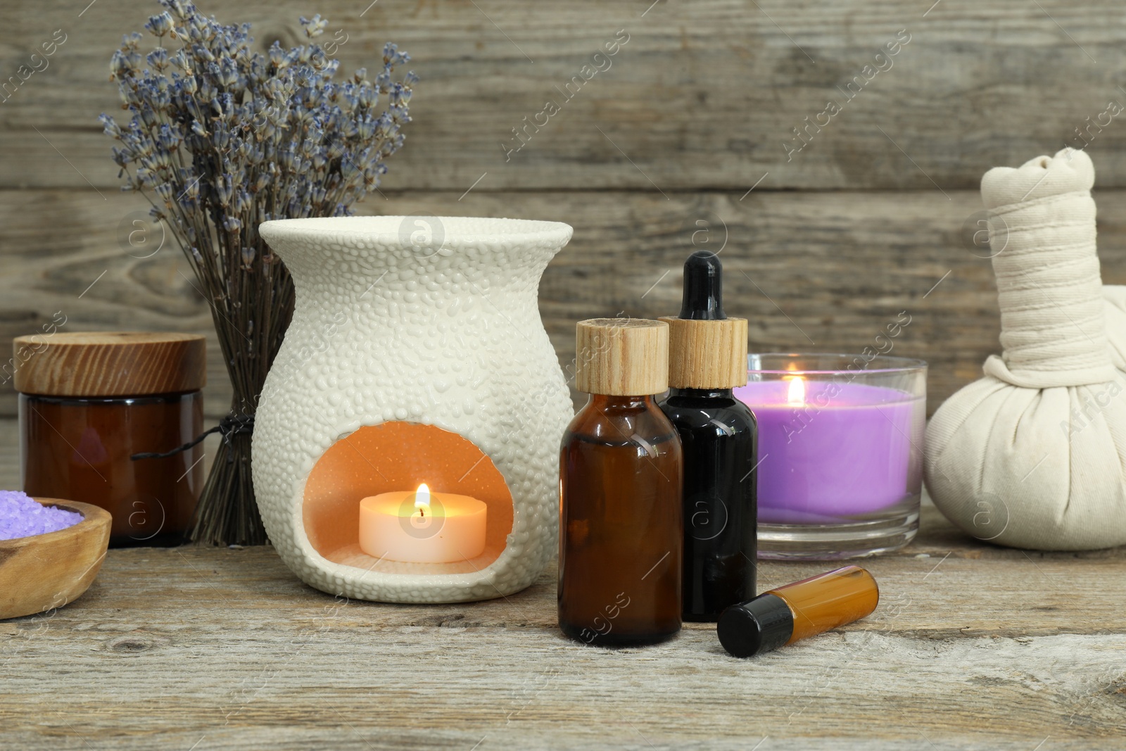 Photo of Different aromatherapy products, burning candle and lavender on wooden table