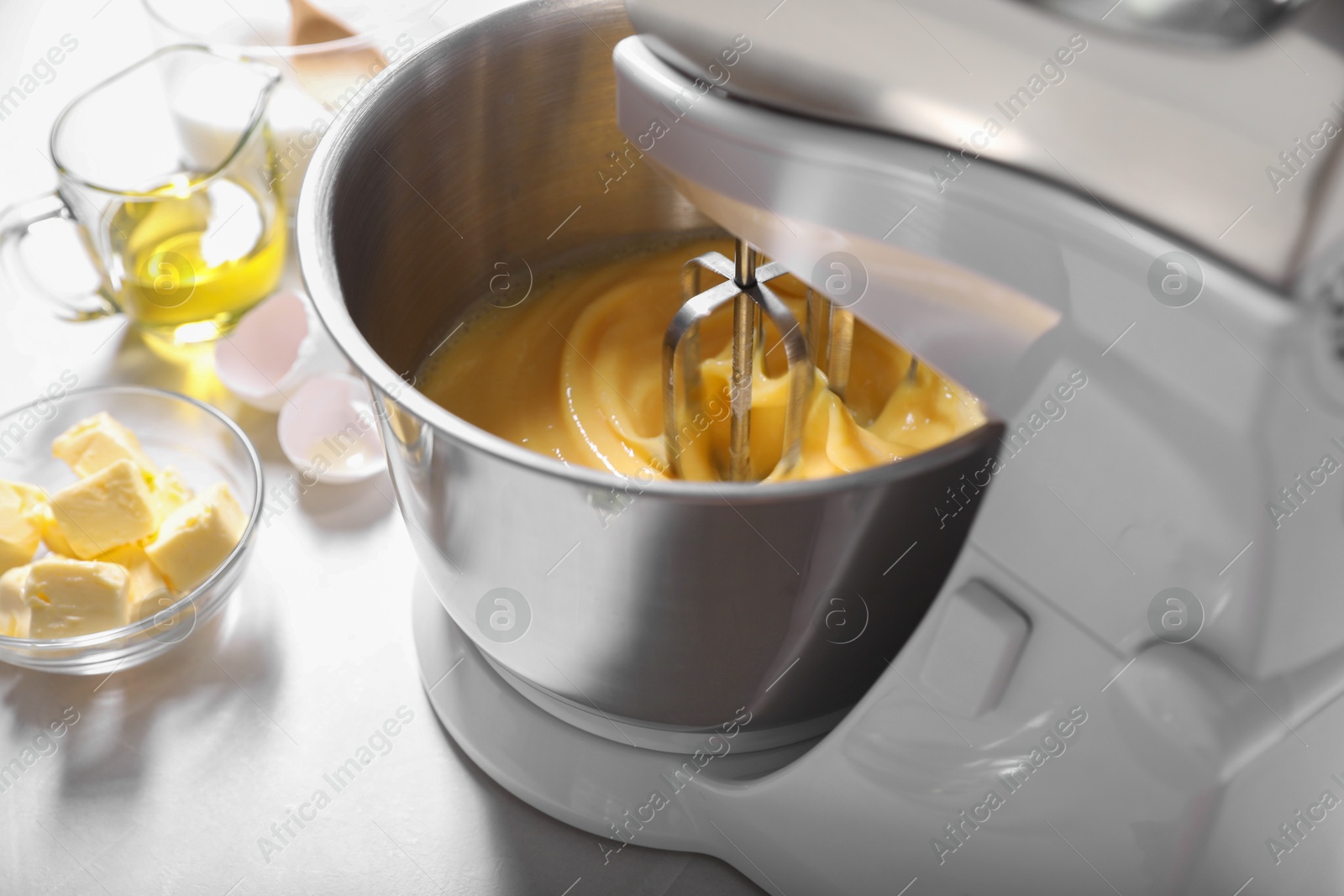 Photo of Making dough in bowl of stand mixer on white table, closeup