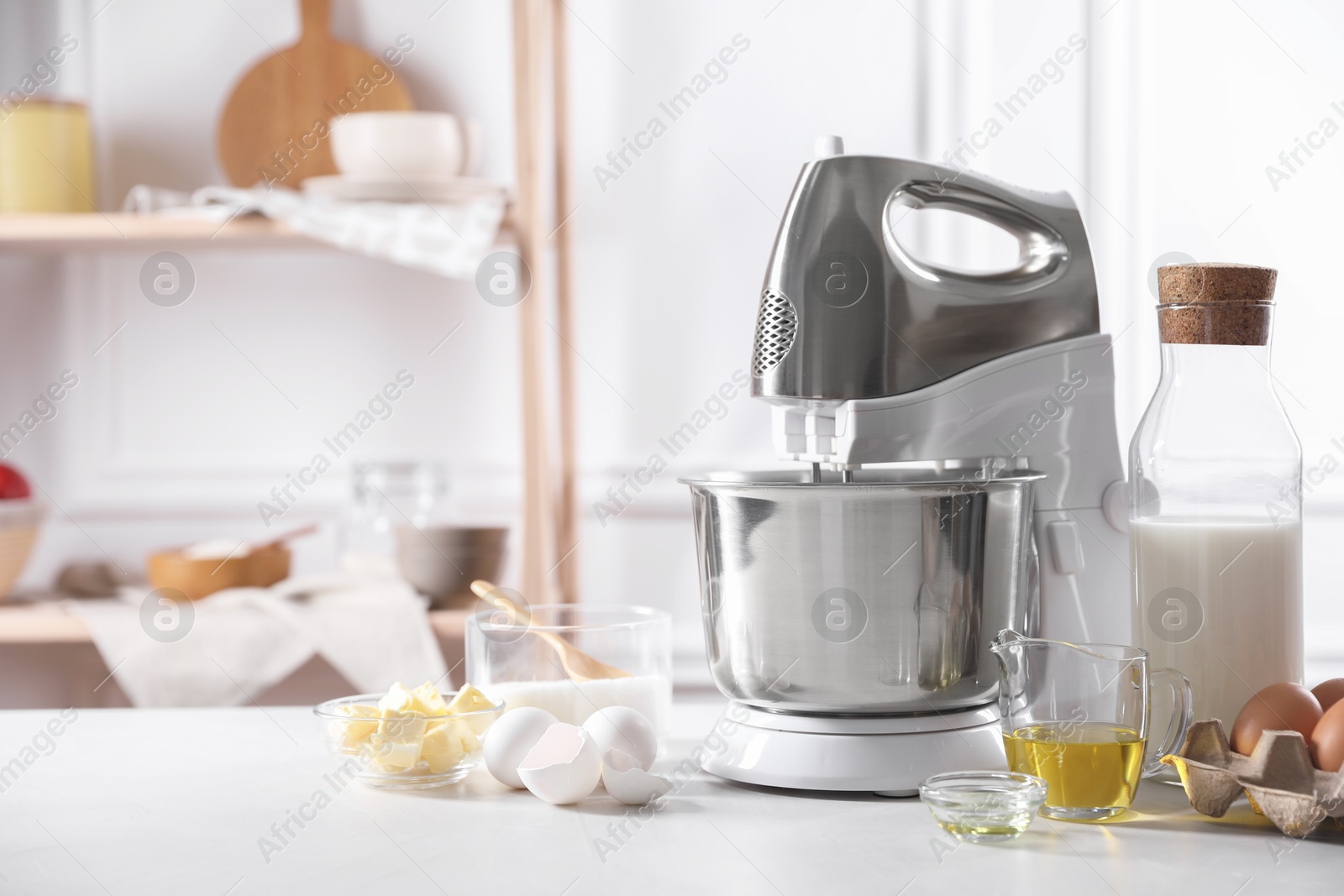 Photo of Modern stand mixer and ingredients for dough on white table indoors. Space for text