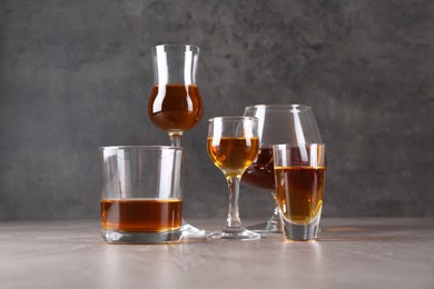 Many different liqueurs in glasses on grey textured table