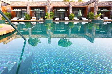 Outdoor swimming pool with wooden deck and sunbeds at resort