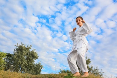 Photo of Cute little girl in kimono training karate outdoors