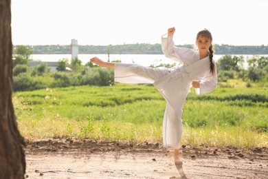 Cute little girl in kimono practicing karate outdoors