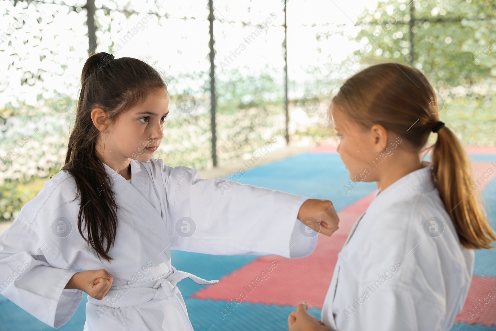 Photo of Children in kimono practicing karate on tatami outdoors