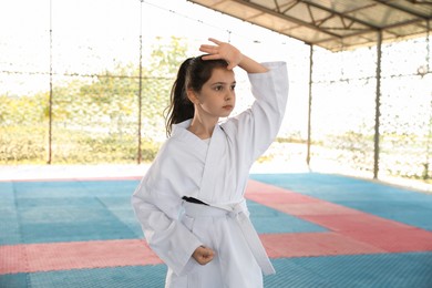 Girl in kimono practicing karate on tatami outdoors