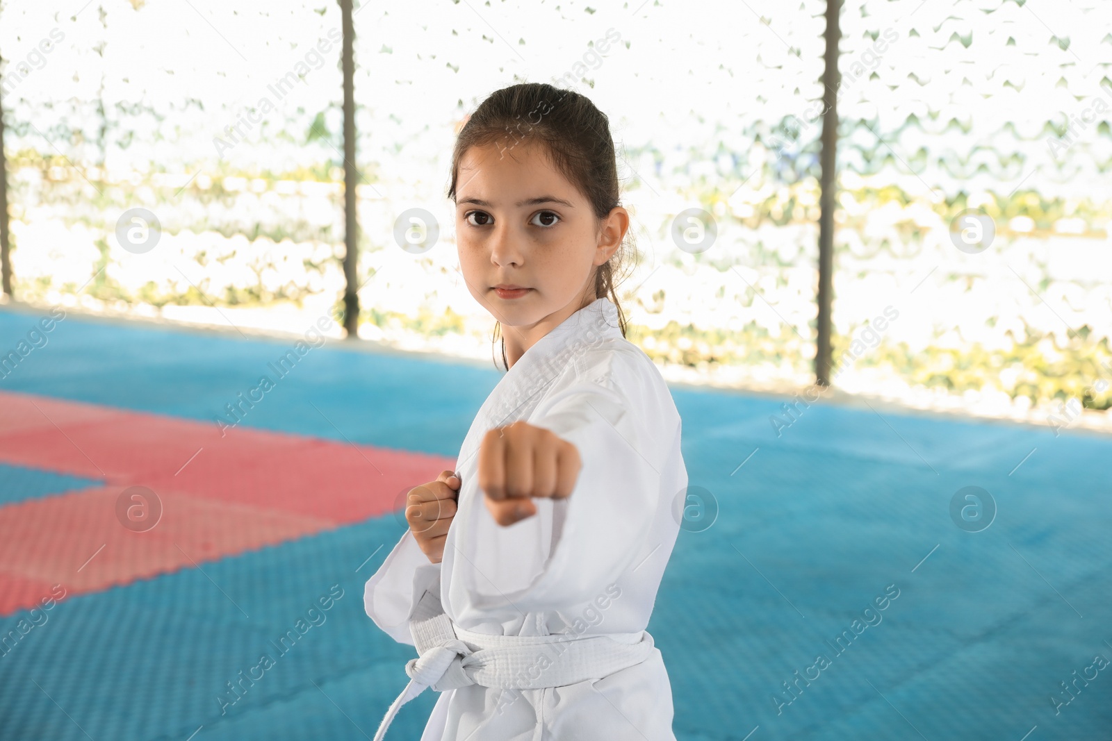 Photo of Girl in kimono practicing karate on tatami outdoors