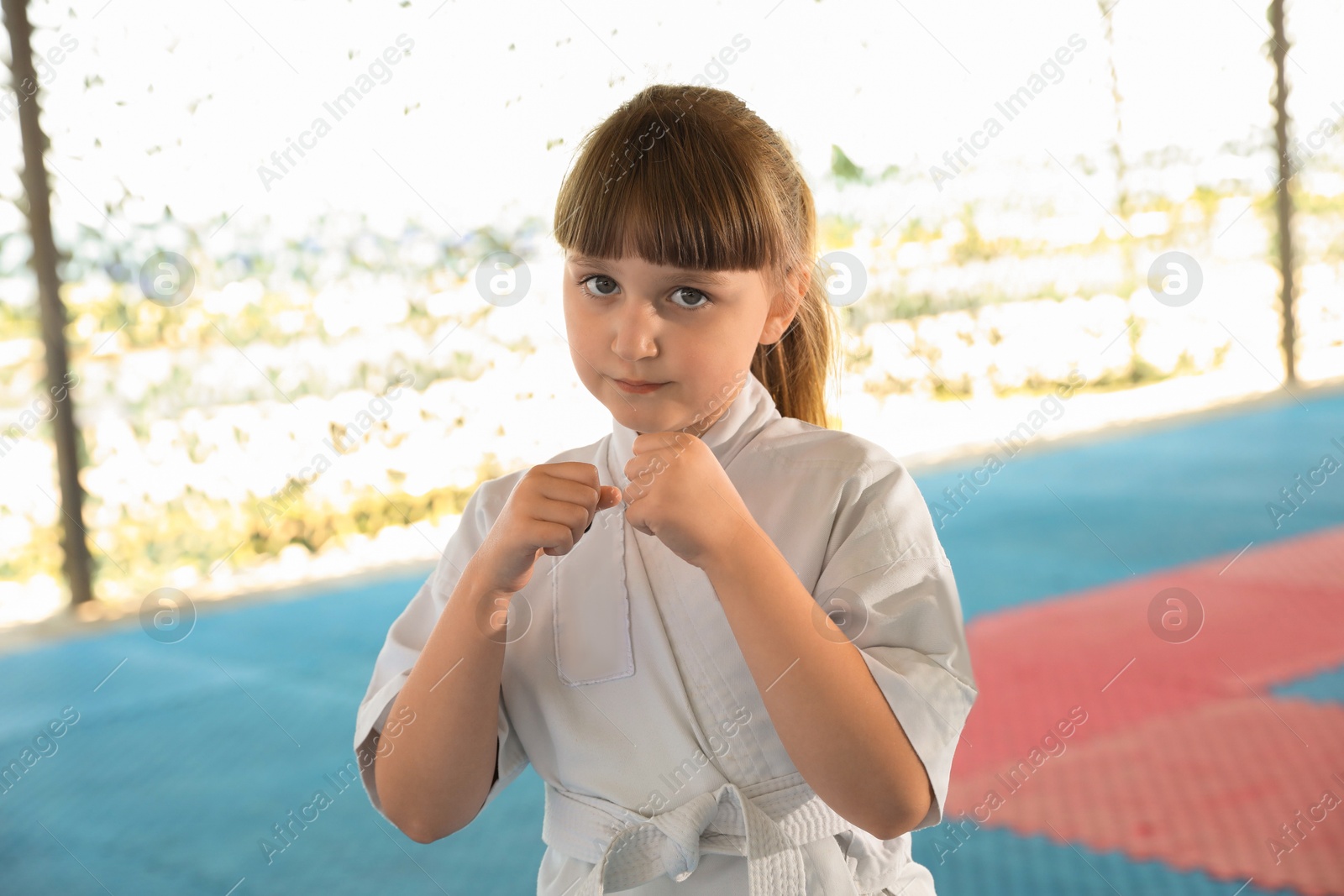 Photo of Girl in kimono practicing karate on tatami outdoors