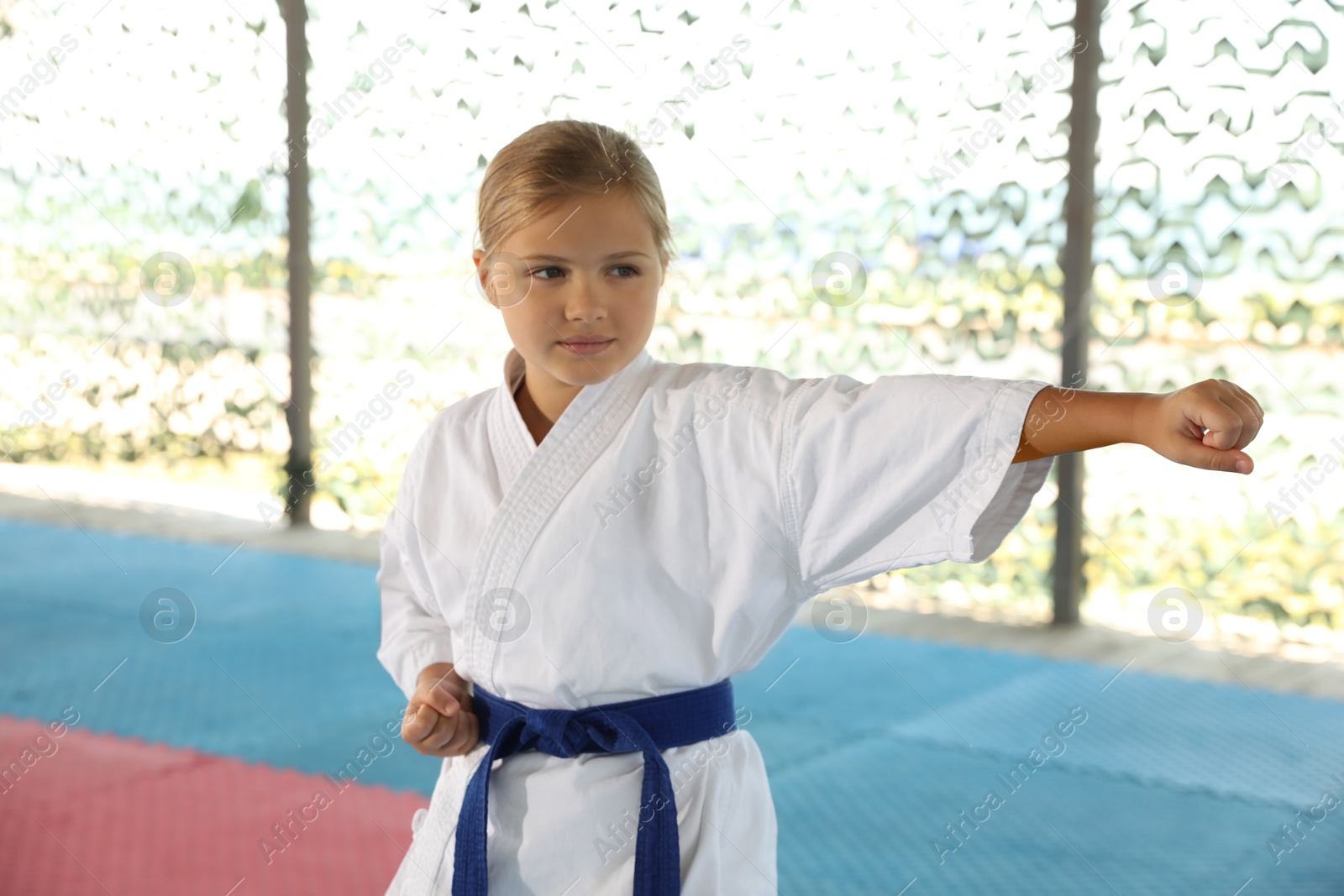 Photo of Girl in kimono practicing karate on tatami outdoors