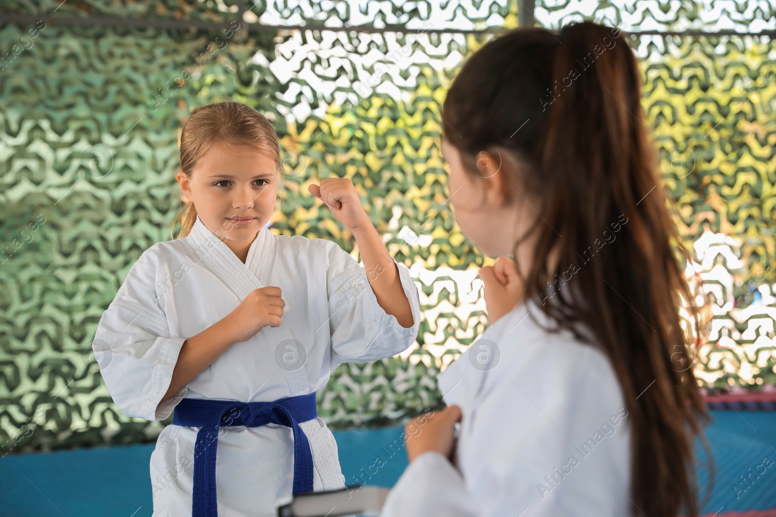 Photo of Children in kimono practicing karate on tatami outdoors