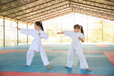 Children in kimono practicing karate on tatami outdoors