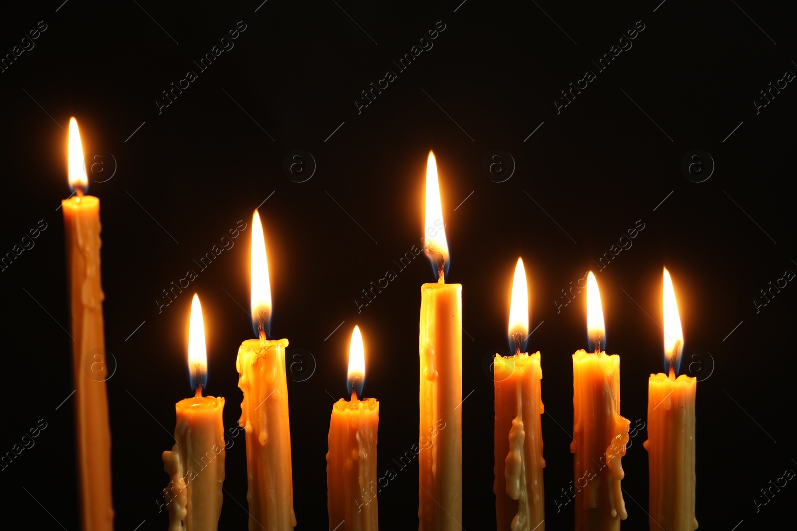 Photo of Many burning church candles on black background