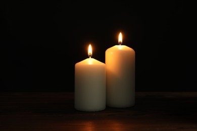 Photo of Two burning church candles on black background