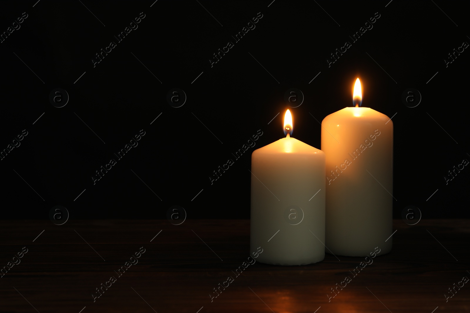 Photo of Two burning church candles on black background, space for text