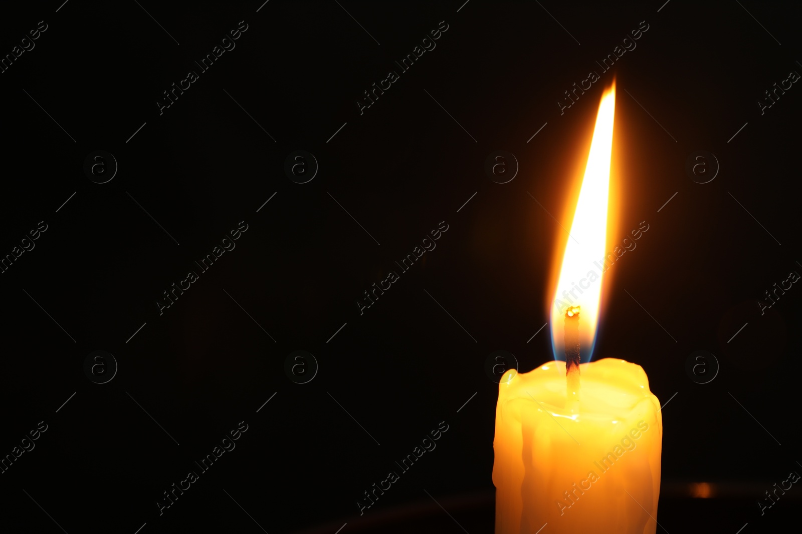 Photo of One burning church candle on black background, closeup. Space for text