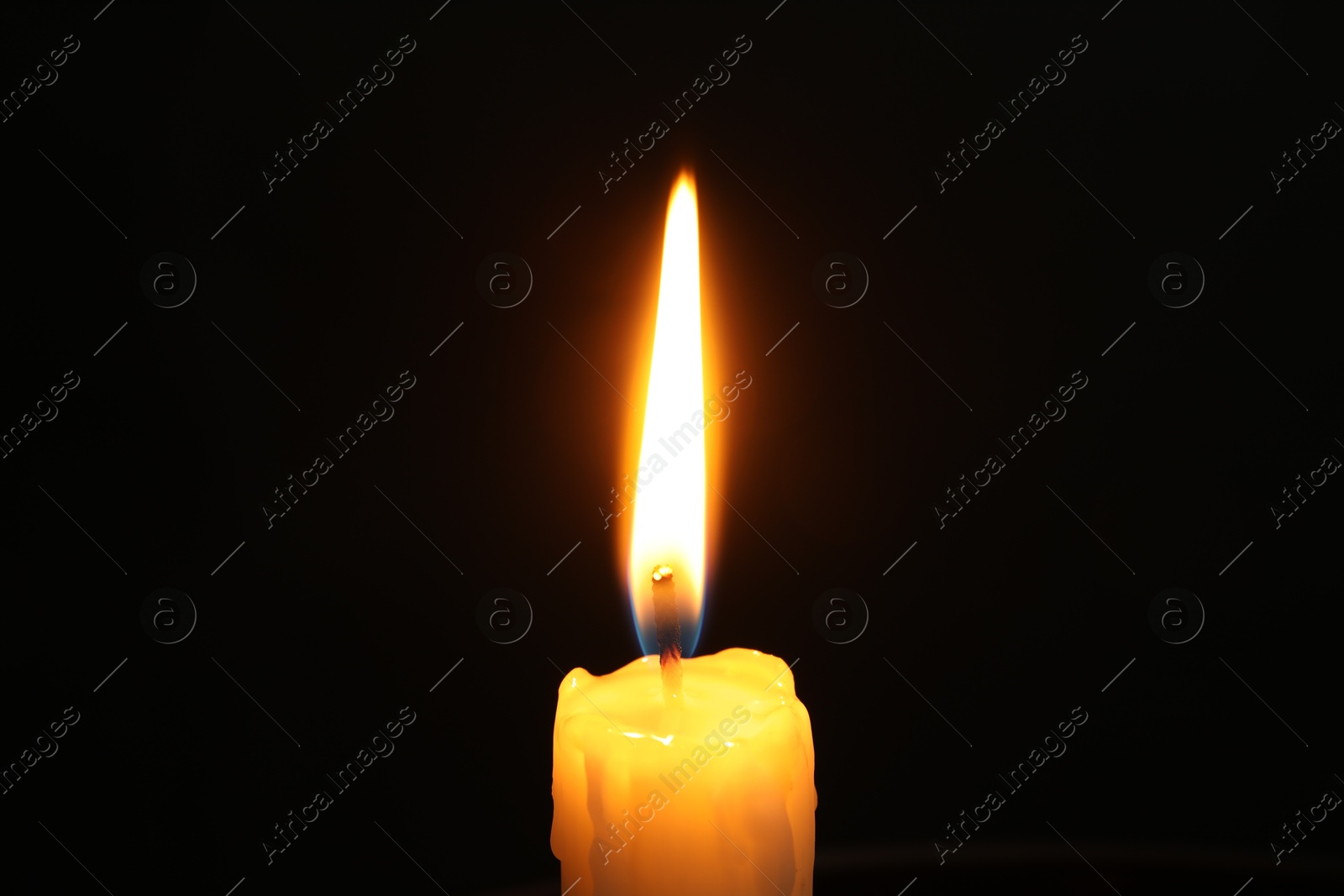 Photo of One burning church candle on black background, closeup