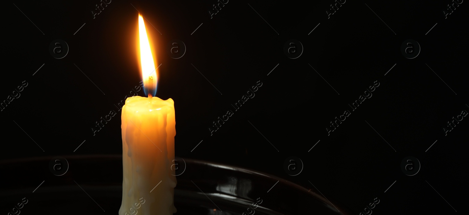 Photo of One burning church candle on black background, closeup. Space for text