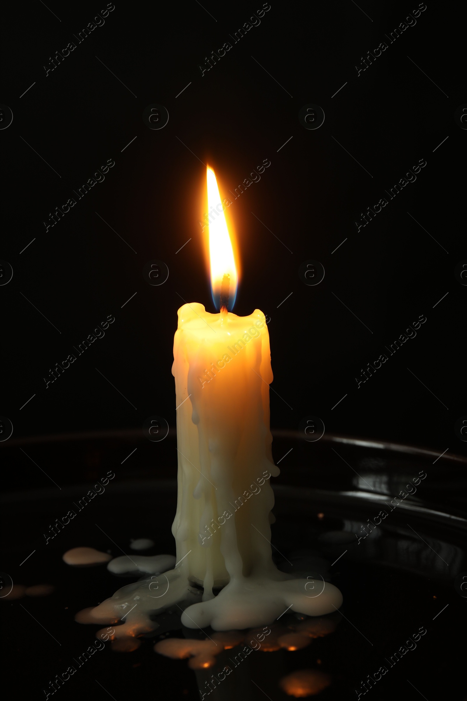 Photo of One burning church candle on black background