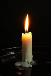 Photo of One burning church candle on black background