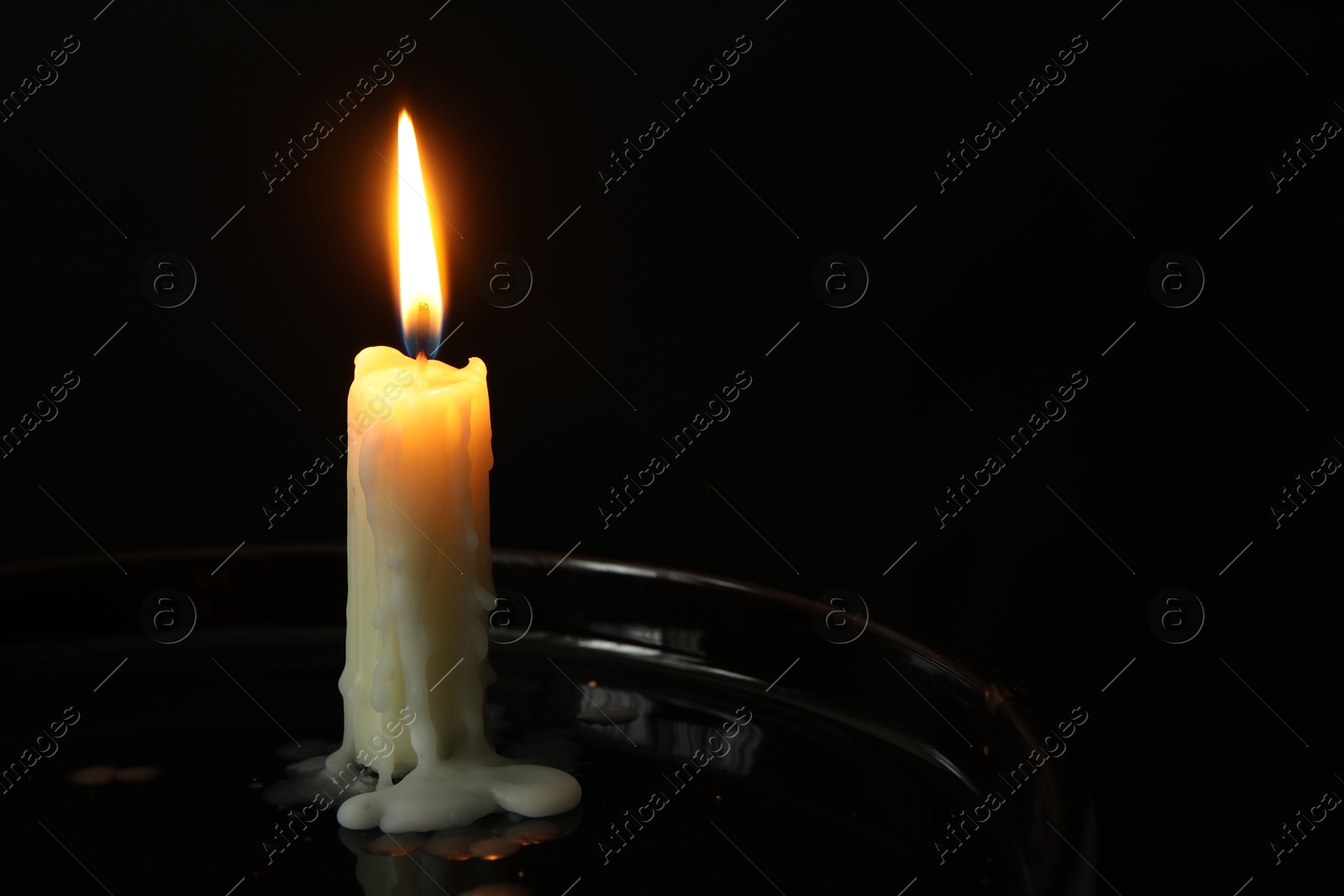 Photo of One burning church candle on black background, space for text