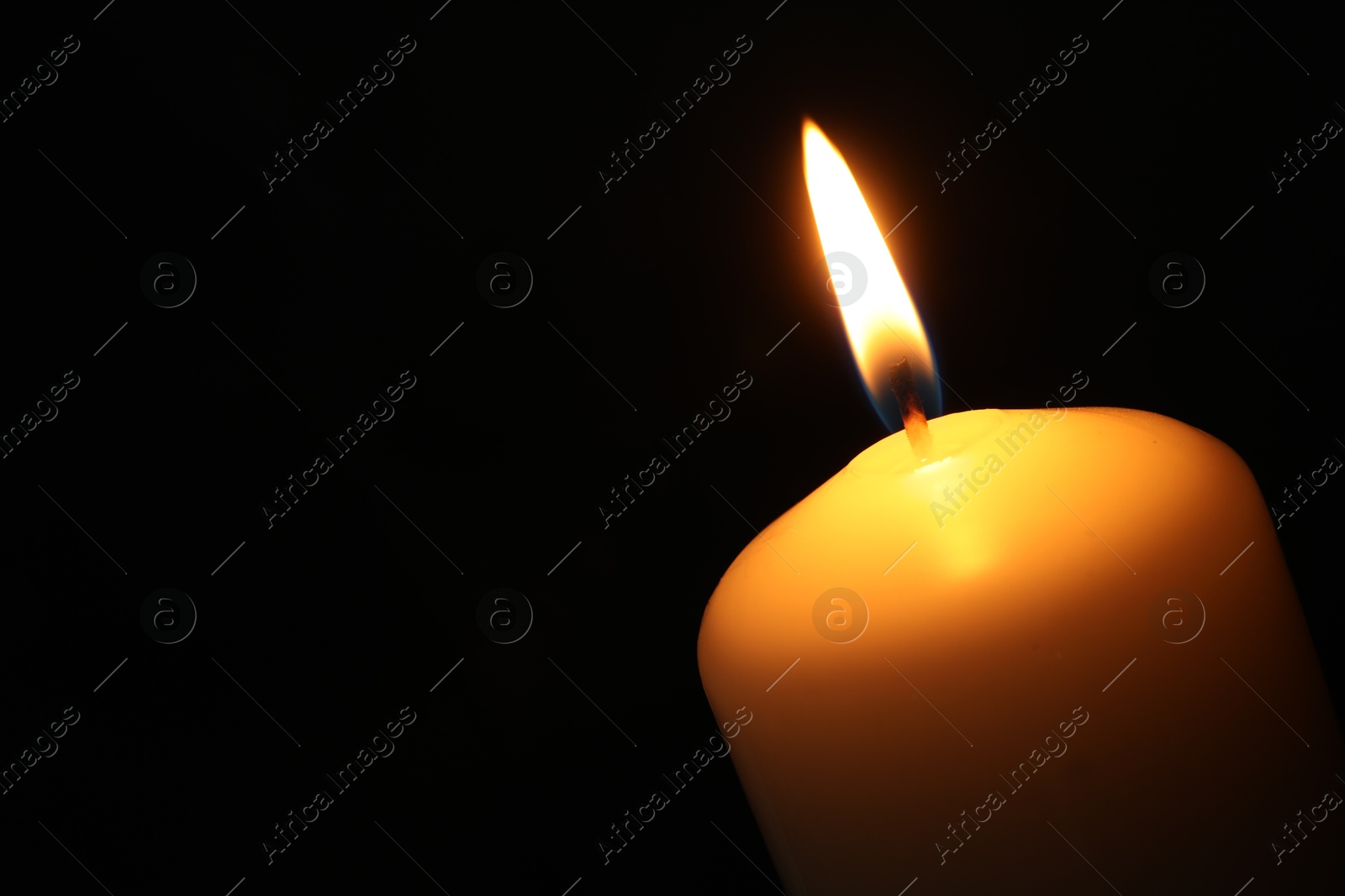 Photo of One burning church candle on black background, closeup. Space for text