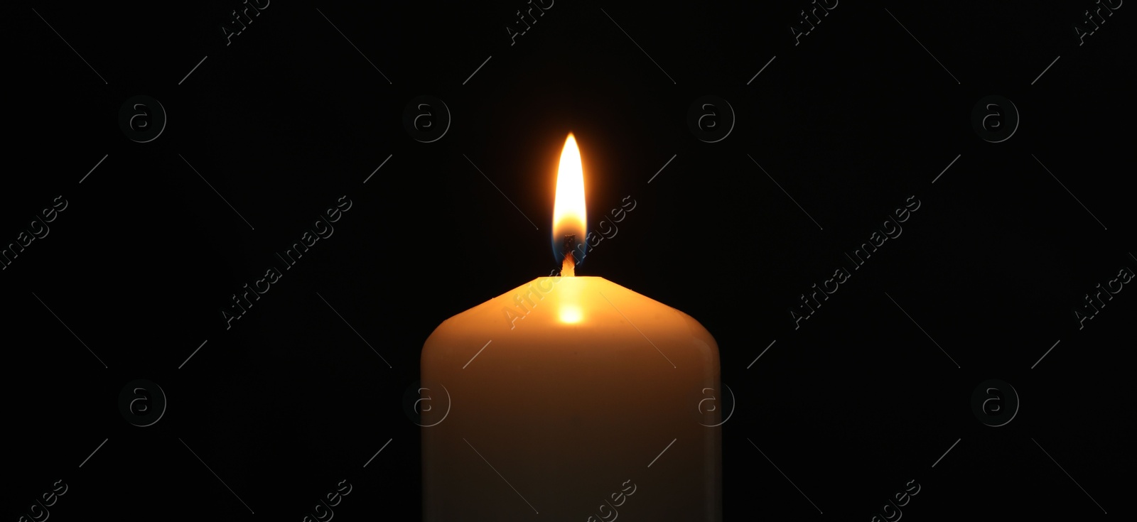 Photo of One burning church candle on black background, closeup