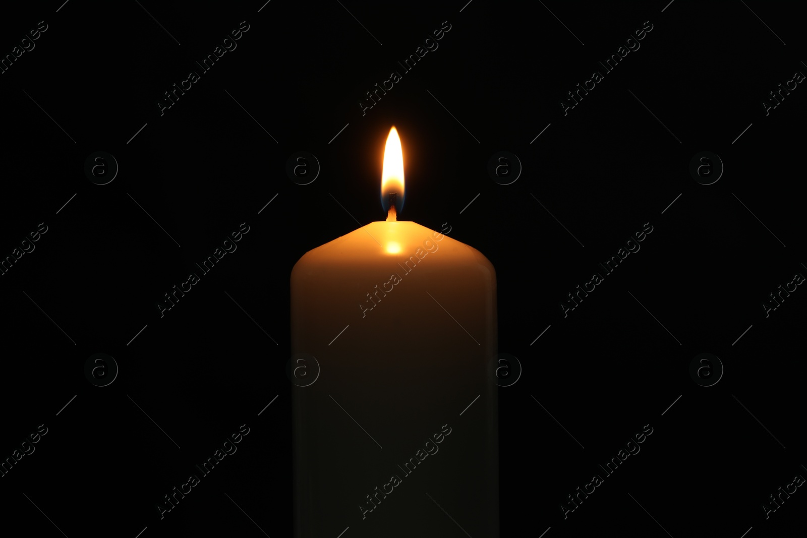 Photo of One burning church candle on black background