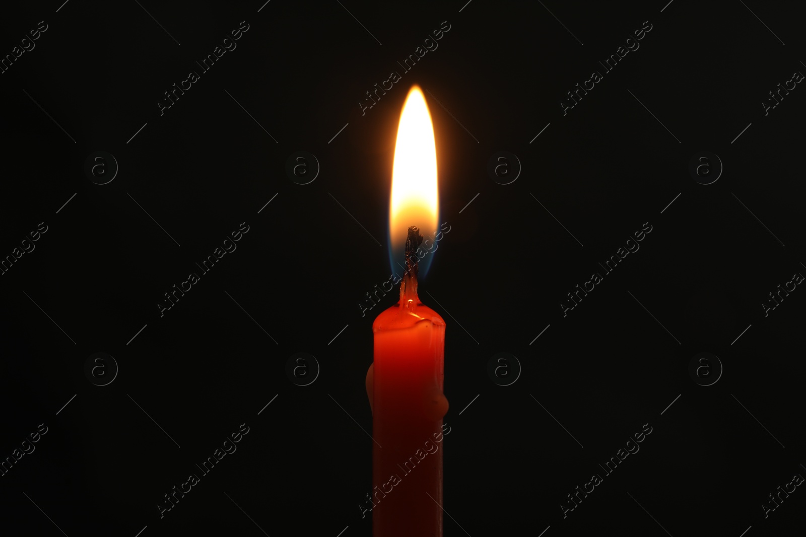 Photo of One burning church candle on black background