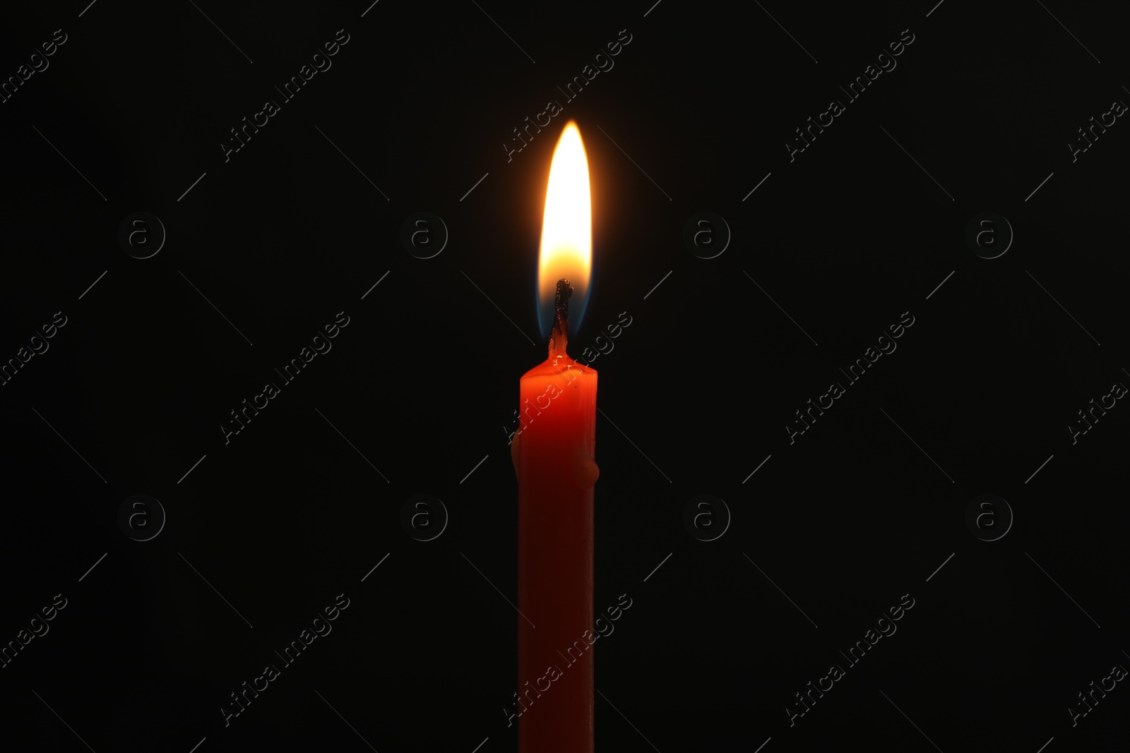 Photo of One burning church candle on black background