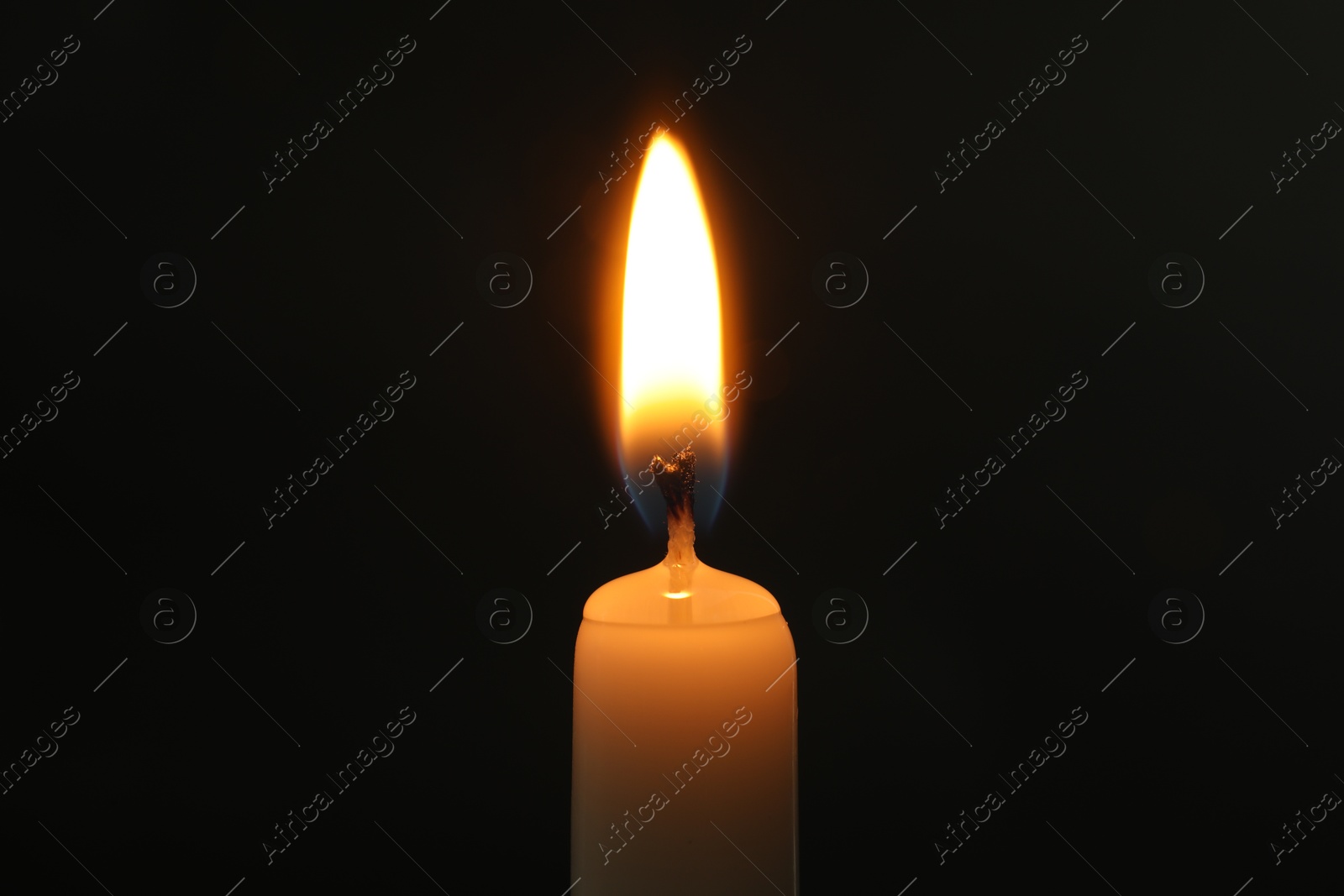 Photo of One burning church candle on black background, closeup