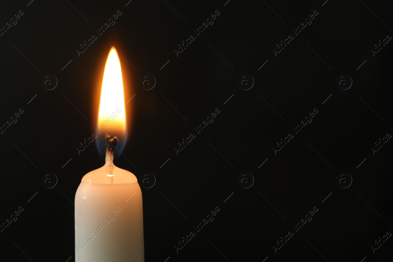 Photo of One burning church candle on black background, closeup. Space for text