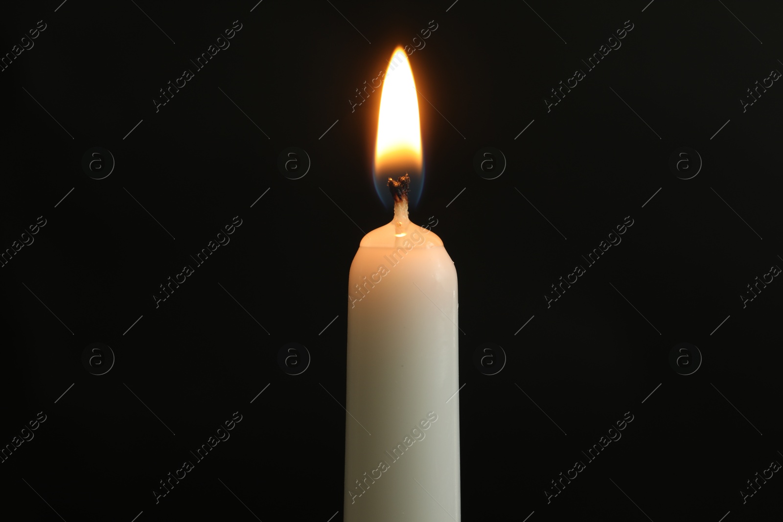 Photo of One burning church candle on black background, closeup