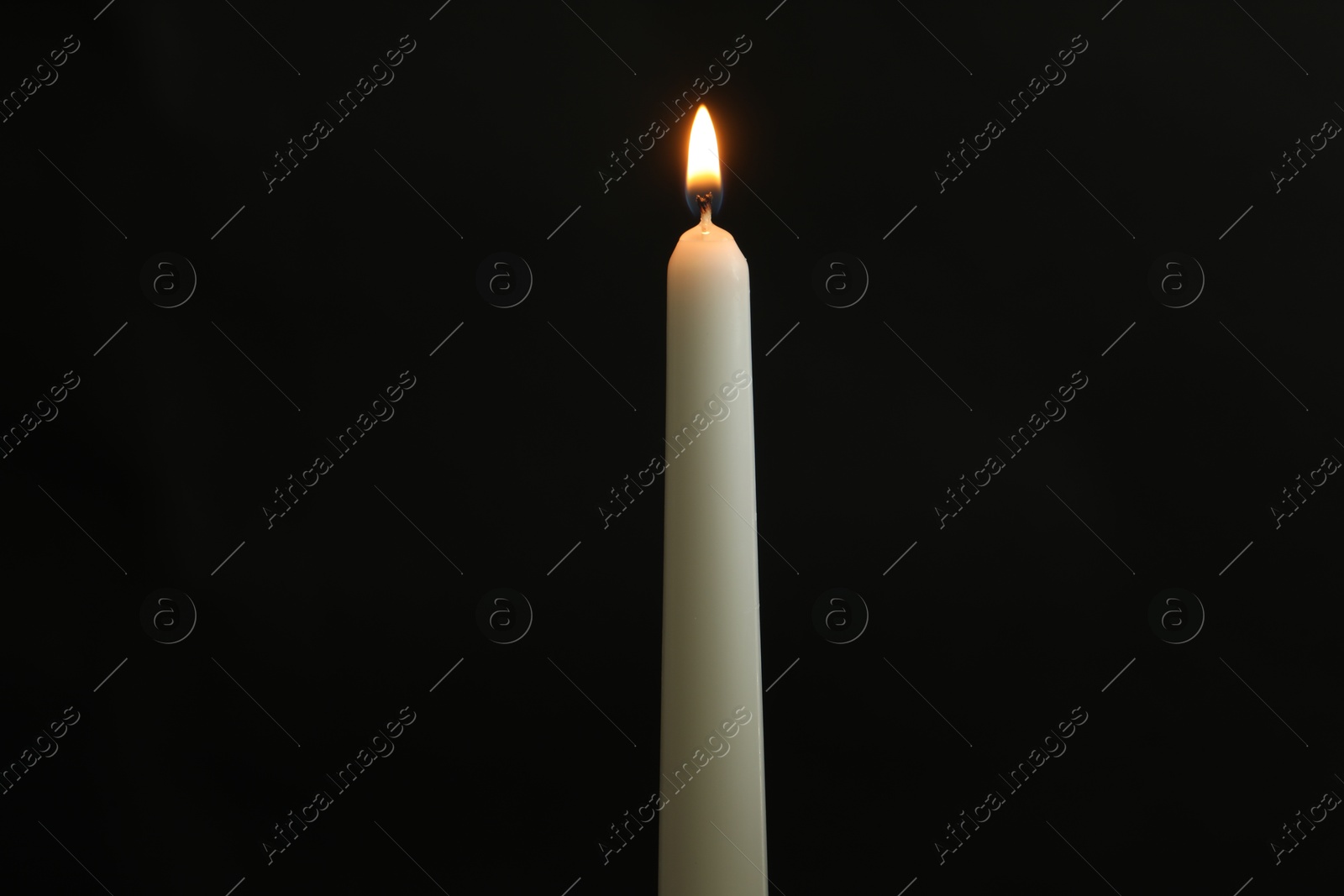 Photo of One burning church candle on black background