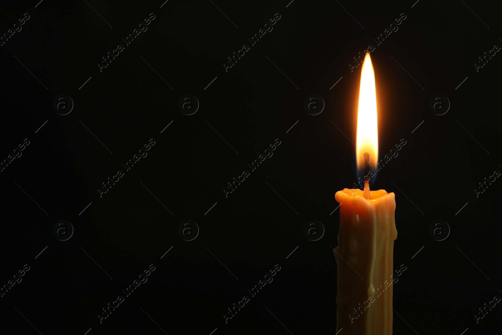 Photo of One burning church candle on black background, space for text