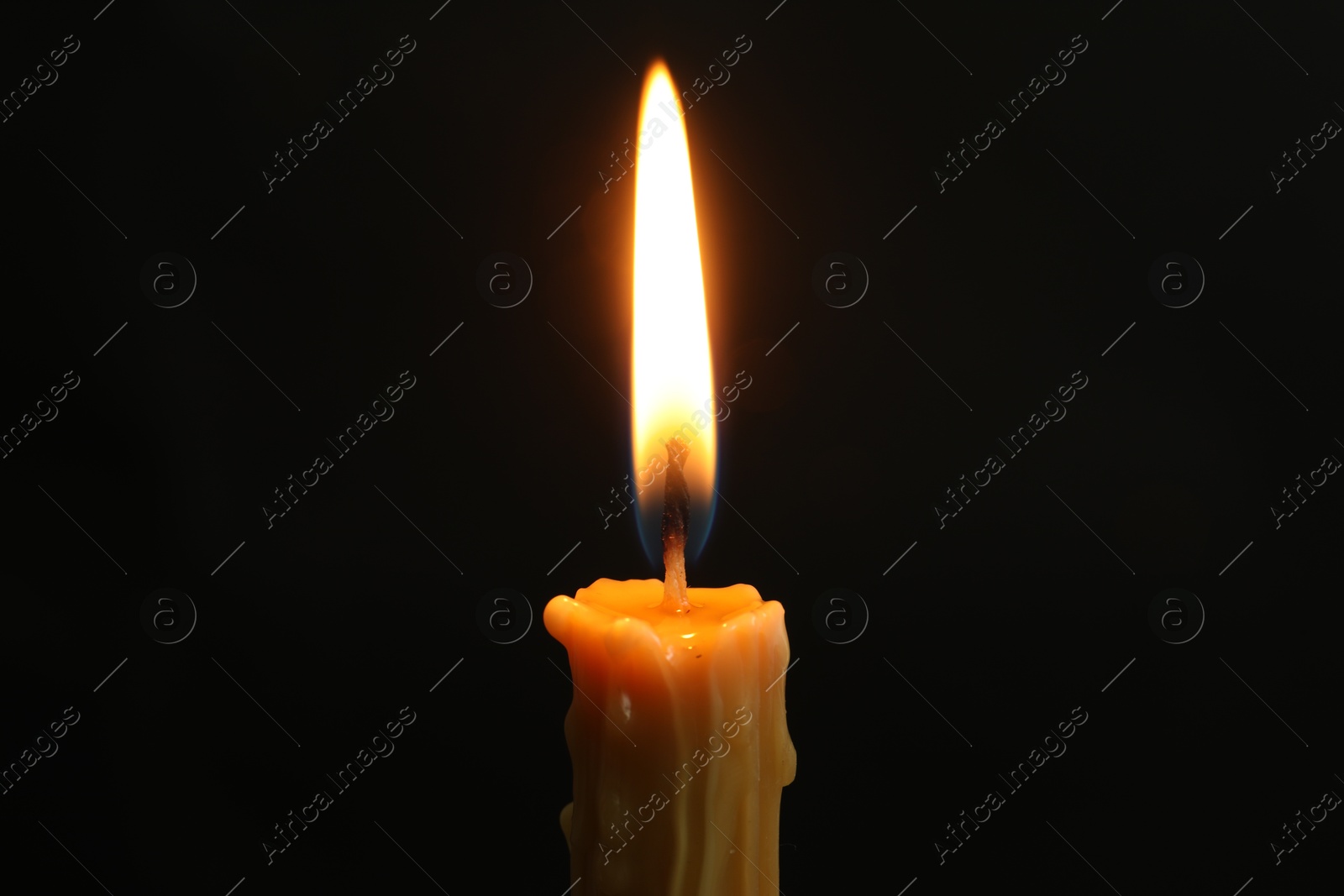 Photo of One burning church candle on black background, closeup