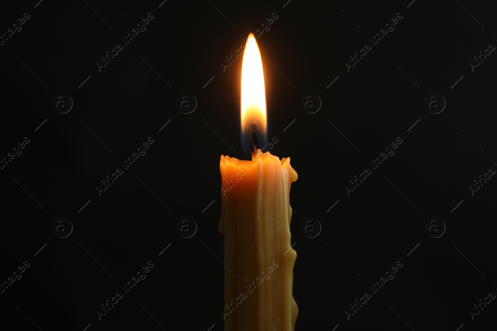 Photo of One burning church candle on black background, closeup