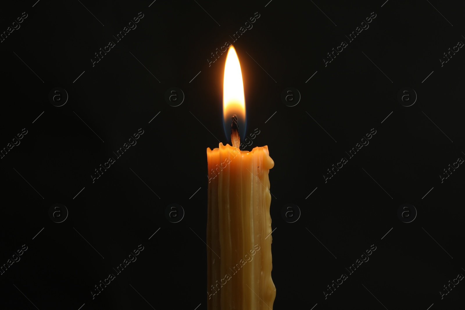 Photo of One burning church candle on black background, closeup