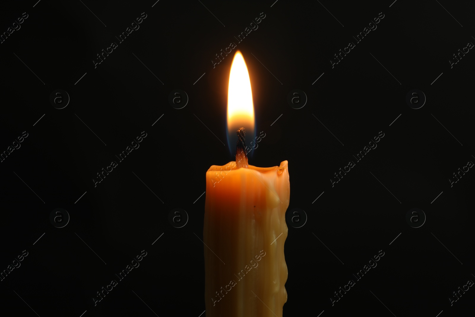 Photo of One burning church candle on black background, closeup