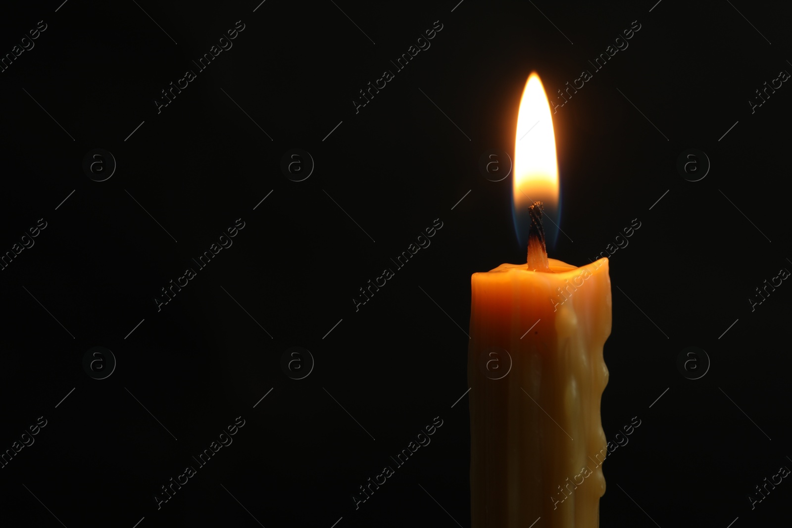 Photo of One burning church candle on black background, closeup. Space for text